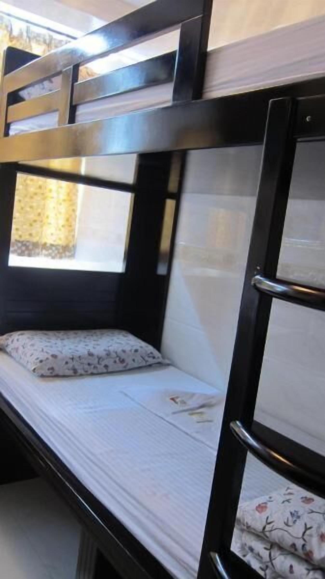 Uma cama beliche com janela, travesseiro e cobertor.