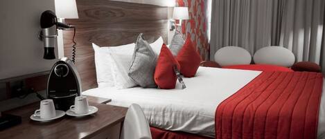 A hotel room with a bed, a desk with a coffee maker, and a hairdryer.