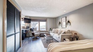 A modern living room with a sofa, coffee table, and a TV mounted on the wall.