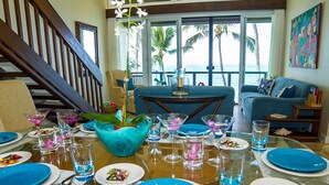 A dining area with a table set for four, a sofa, and a view of the ocean. - STUNNING OCEANFRONT * Poipu's Best View * New Air Conditioning throughout (koloa)