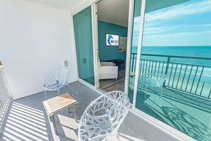 Un balcon avec vue sur la mer, une chaise, une petite table et une enseigne indiquant « Big Fish Resort ».