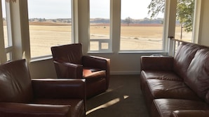 A room with two leather sofas facing a large window with a view of a desert landscape.