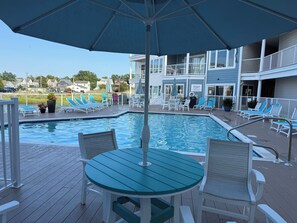 Un área de piscina con sillones de descanso, una mesa y sombrillas.