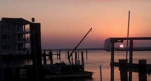 A waterfront building with multiple floors, docked boats, and a crane.