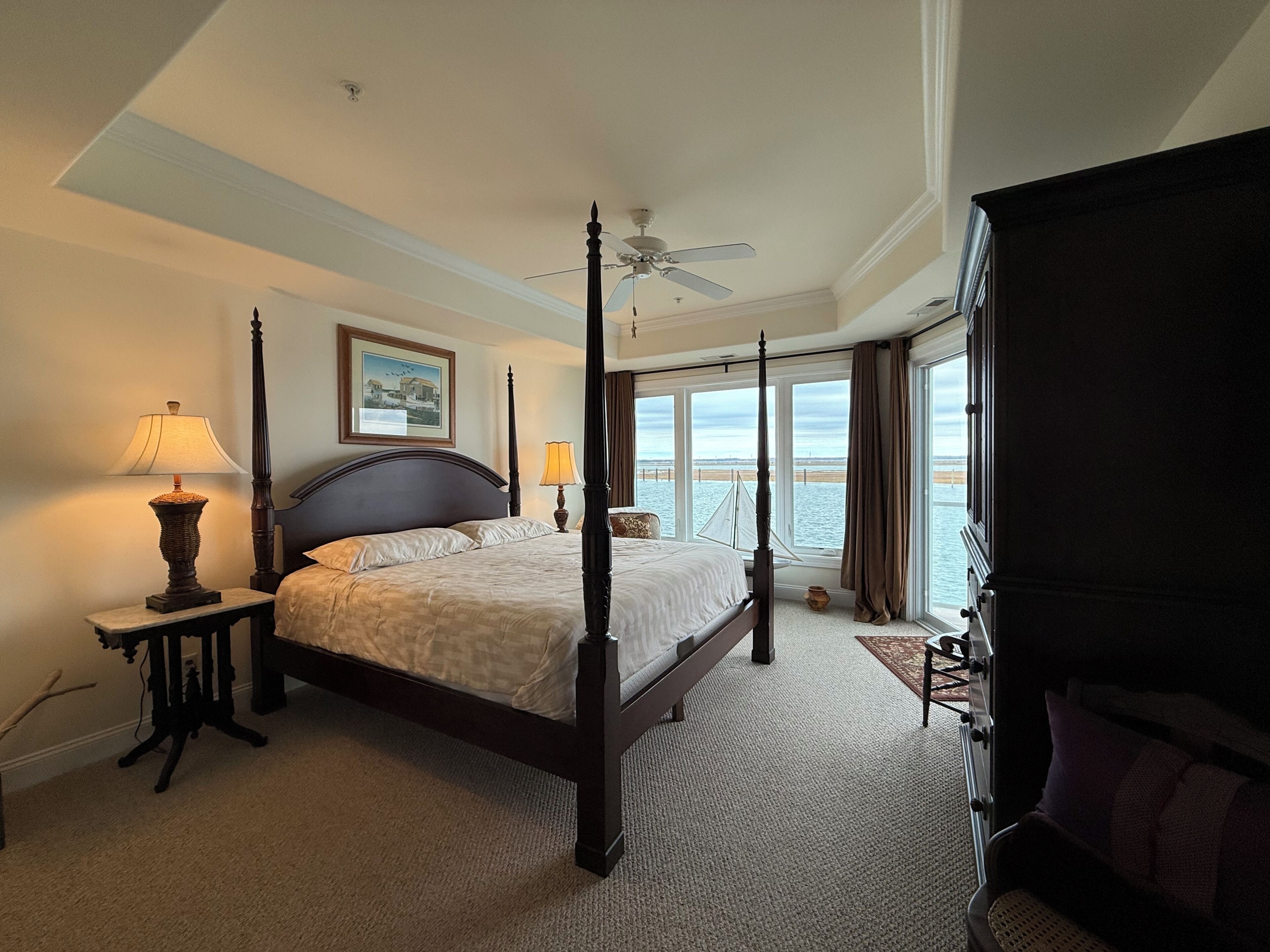 A four-poster bed with a view of the sea through large windows.