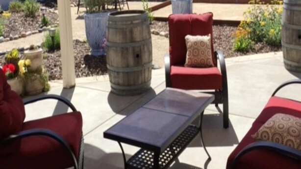 Un espace extérieur aménagé en terrasse, avec une pergola, des chaises rouges, une table et des plantes en pot.
