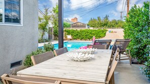Un patio con mesa y sillas de madera, una piscina y un cartel que dice 'Welcome'.