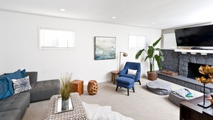 Una sala de estar moderna con un sofá gris, un sillón azul y una chimenea.