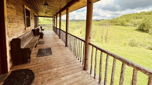 Eine hölzerne Veranda mit Bänken und Blick auf eine grüne Landschaft.