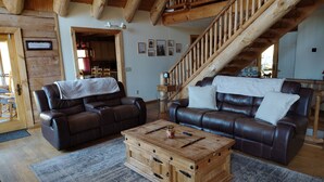 Ein gemütliches Wohnzimmer mit Ledersofas, einem Holztisch und einer Treppe.