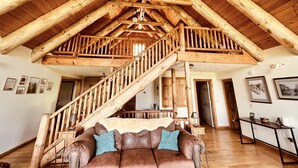 Ein großzügiges Loft mit hohen Holzbalken und einer zentralen Treppe.