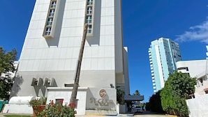 A tall white building with a modern design, featuring a central vertical window and a logo on the facade.