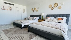 A bedroom with two beds, a rug, and wall decor.