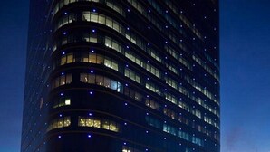 Une piscine offrant une vue sur un immeuble de grande hauteur, de nuit.