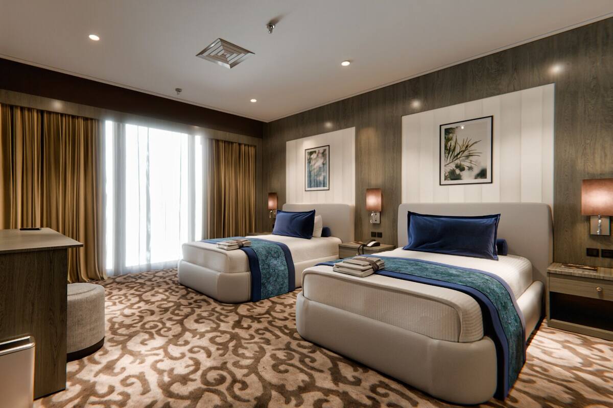 Une chambre d’hôtel avec deux lits, un bureau et une poubelle.