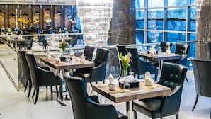 Un restaurant moderne avec un lustre, des chaises noires et un sol en marbre.