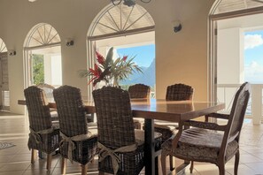 A dining area with a large table, wicker chairs, and a view of the outdoors.