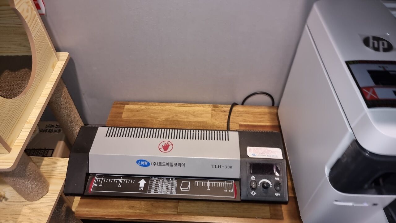 A printer on a wooden table with a cable connected to it.