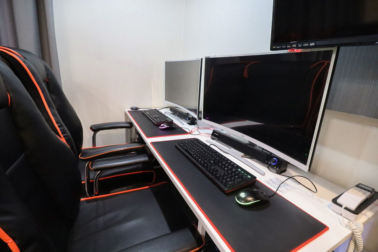 A gaming setup with two monitors, a keyboard, a mouse, and a chair.