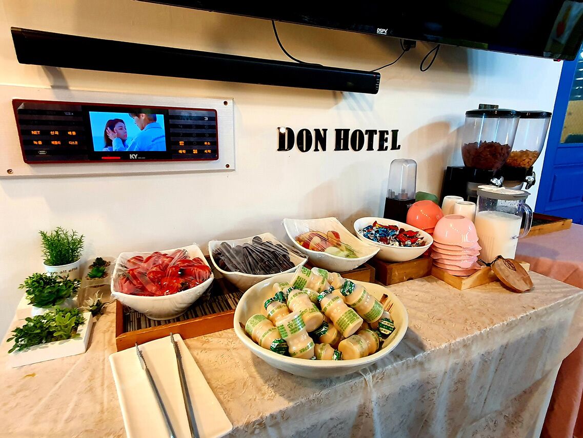 A hotel buffet with various food items and a television screen displaying a program.