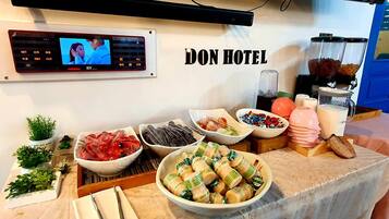 A hotel buffet with various food items and a television screen displaying a program.