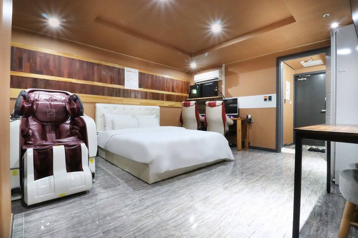 Ein Hotelzimmer mit Bett, Massagesessel, Schreibtisch und Fernseher.