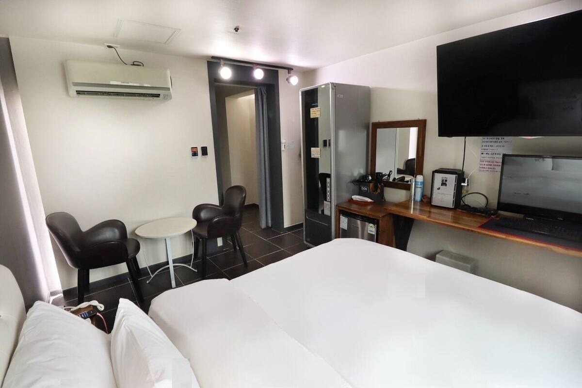 Ein Hotelzimmer mit Bett, Schreibtisch, Computer, Fernseher und Klimaanlage.