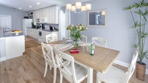 A modern kitchen with white cabinets, a wooden dining table, and a chandelier. - MARCH SPECIAL  AVAILABLE! (Davenport)
