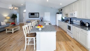 A modern kitchen with white cabinets, a granite countertop, and a dining area with a wooden table and chairs. - MARCH SPECIAL  AVAILABLE! (Davenport)