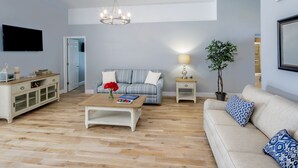 A living room with a sofa, a coffee table, a TV, a chandelier, a lamp, and a potted plant. - MARCH SPECIAL  AVAILABLE! (Davenport)