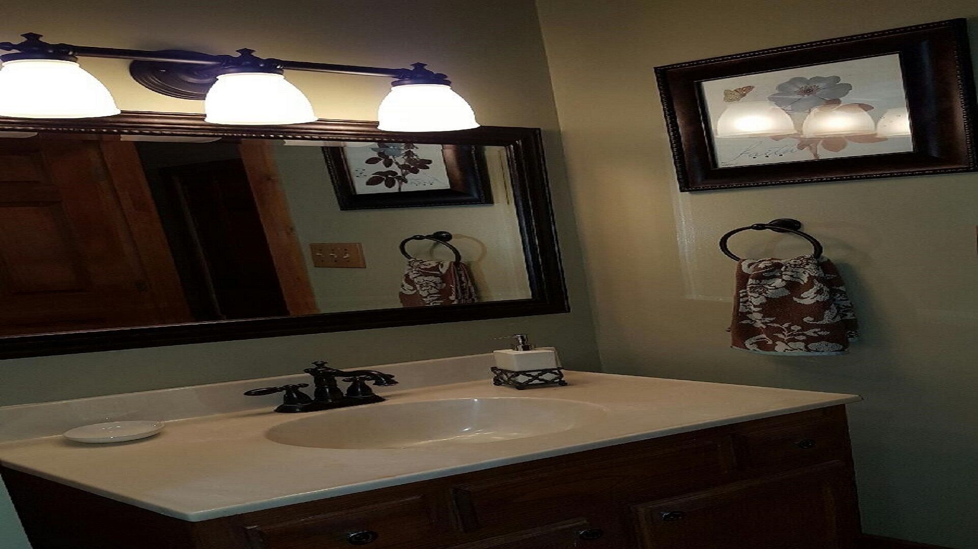 A bathroom with a large mirror, a sink, and a towel rack.