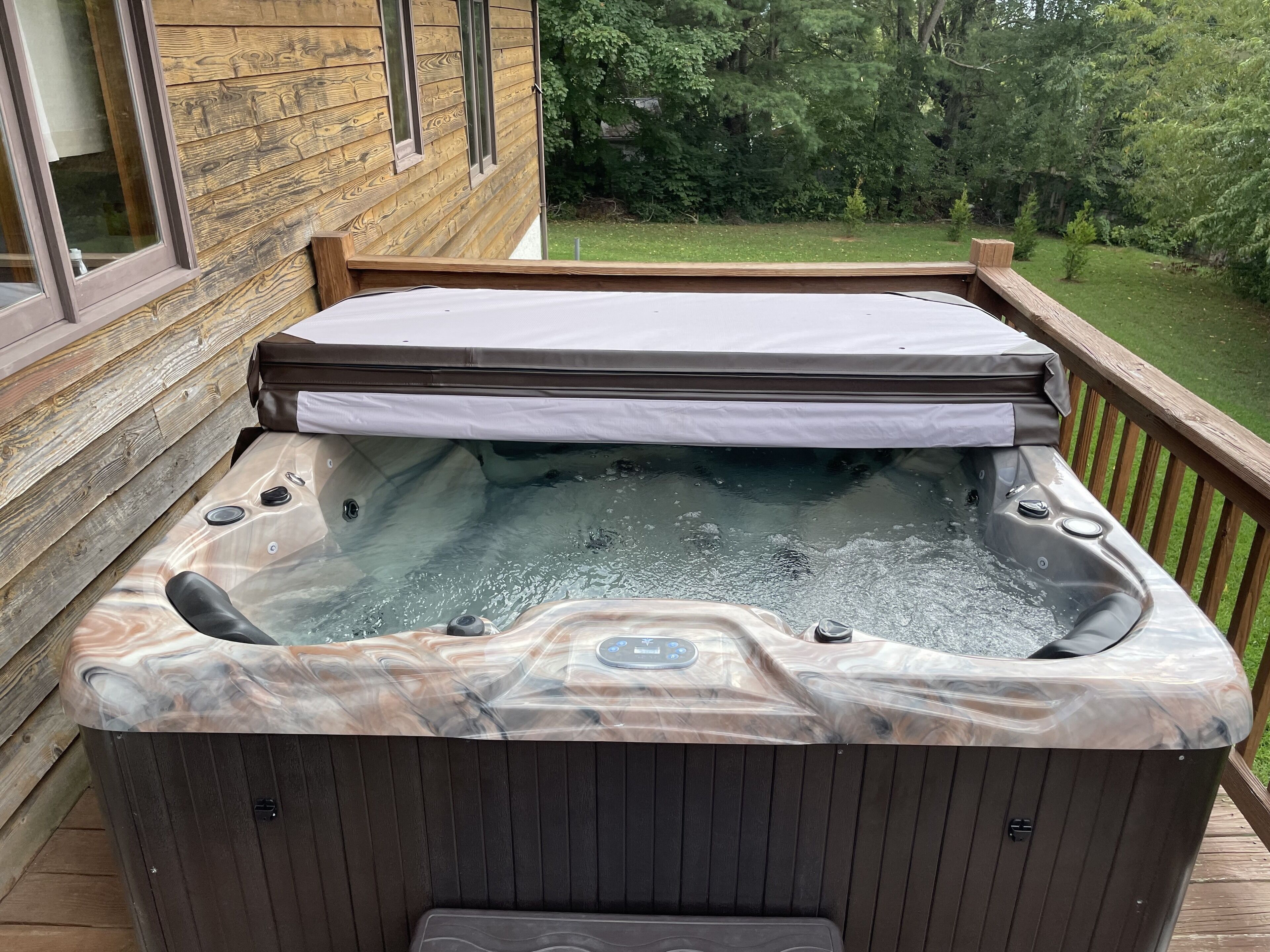 Ein Whirlpool auf einer Holzterrasse mit Blick auf eine bewaldete Landschaft.