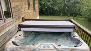 A hot tub on a wooden deck with a view of a forested area. - Lovely cottage in West Asheville. Hot Tub. Pool open for SUMMER! (Asheville)