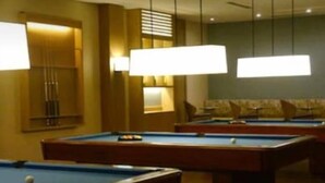 Een poolruimte met meerdere tafels en verlichting erboven.