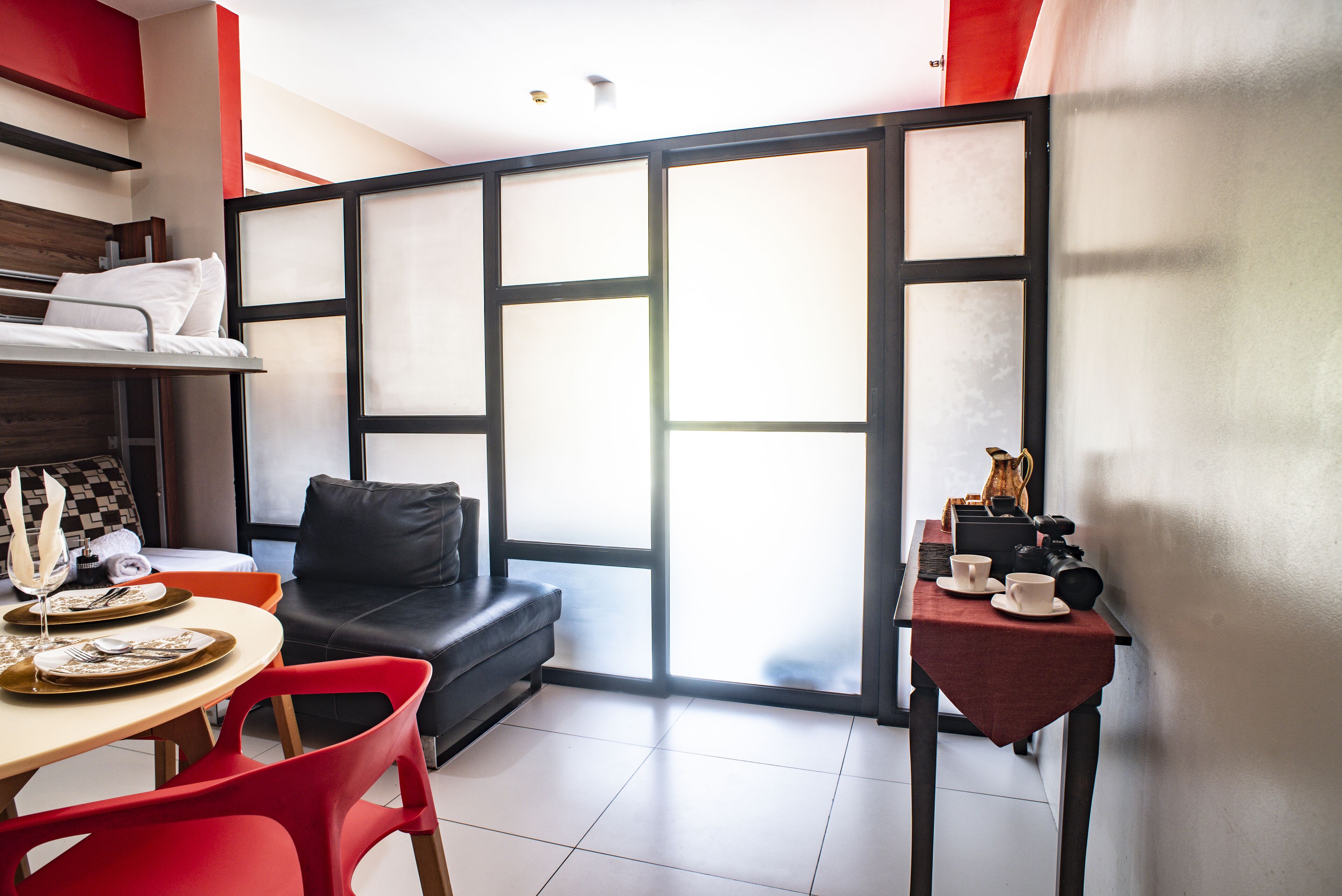 A modern room with a sofa, dining table, and a small table with cups and a camera.