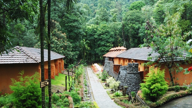 Un sendero conduce a edificios de estilo tradicional, rodeados de abundante vegetación.