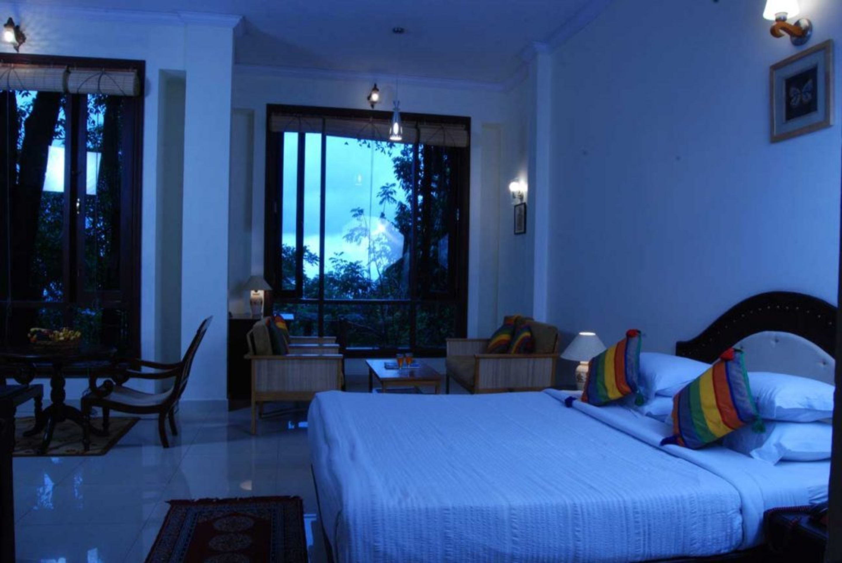 Habitación de hotel con una cama grande, un escritorio, una silla y vistas al exterior.