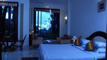 Habitación de hotel con una cama grande, un escritorio, una silla y vistas al exterior.