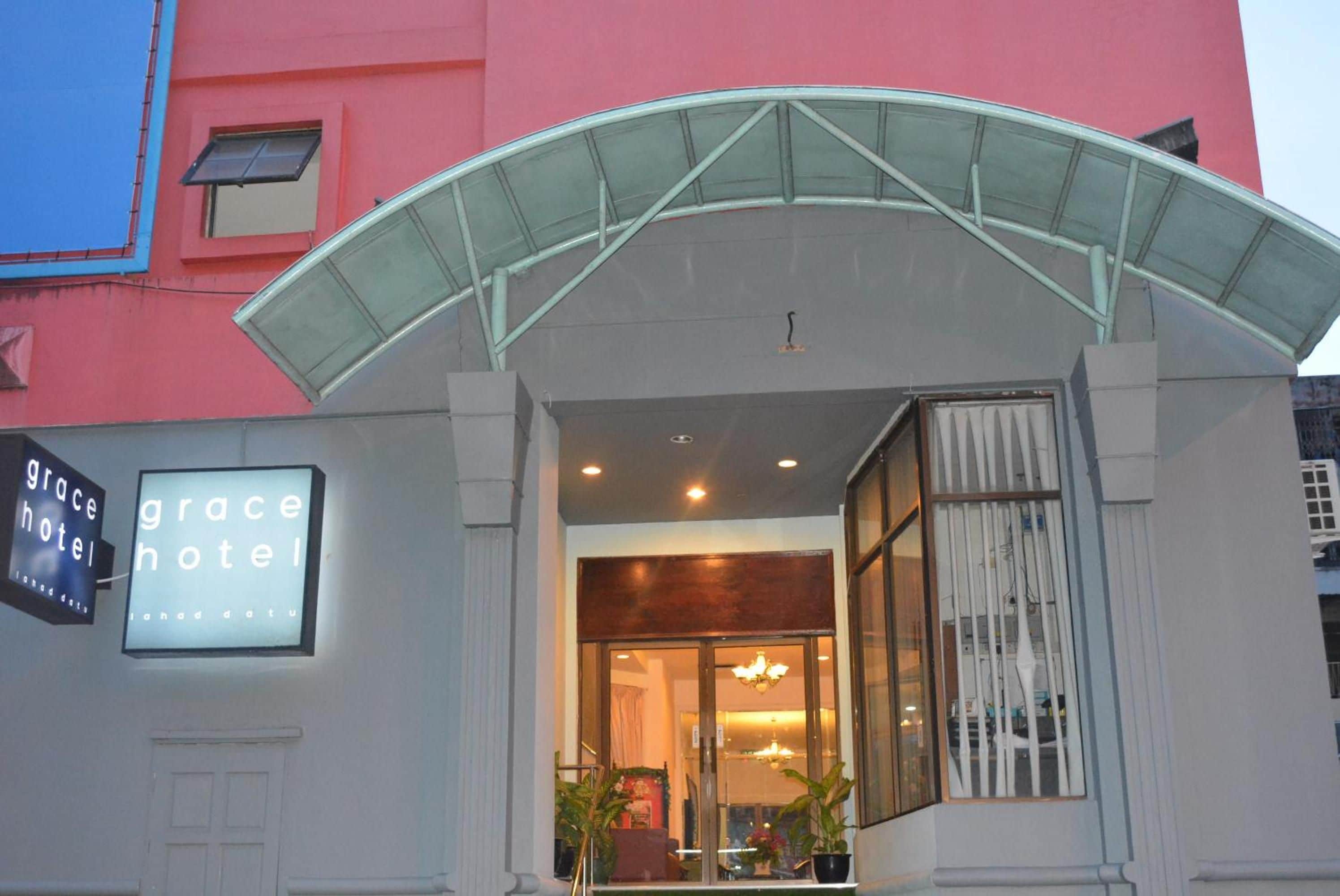 L’entrée d’un hôtel, avec un auvent en verre, une enseigne et un intérieur visible, agrémenté d’un lustre.