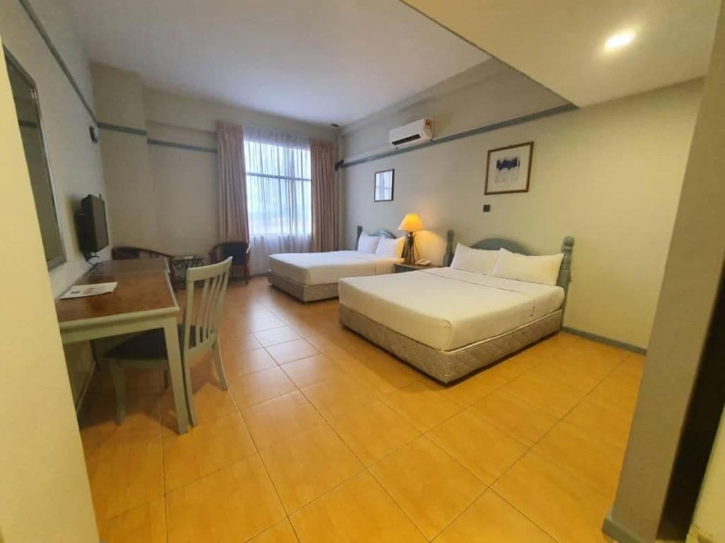 Ein Hotelzimmer mit einem Bett, einem Schreibtisch, einem Sessel und einem Fernseher.