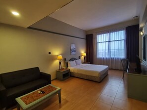 A hotel room with a bed, a sofa, a coffee table, a desk, and a TV. - Grace Hotel Lahad Datu (Lahad Datu)
