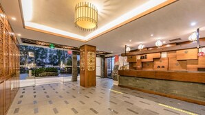 Een hotel lobby met een receptiebalie, een grote zuil en een vloer met een patroon.