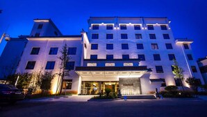 Een hotel met meerdere verdiepingen, een moderne gevel, grote ramen en een goed verlichte entree.