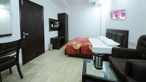 A bedroom with a bed, a TV, a desk, a chair, and a sofa. - Hotel Winner Inn (Amritsar)