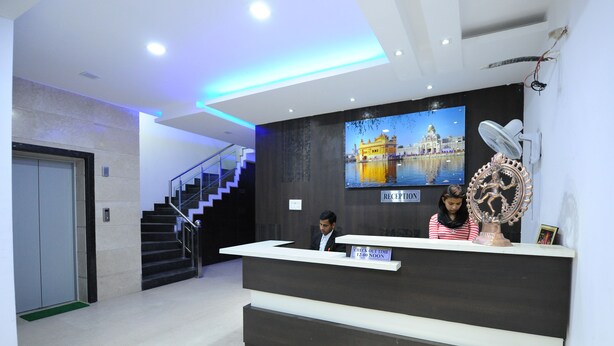 A reception area with a reception desk, a staircase, and a reception sign. - Hotel Winner Inn (Amritsar)