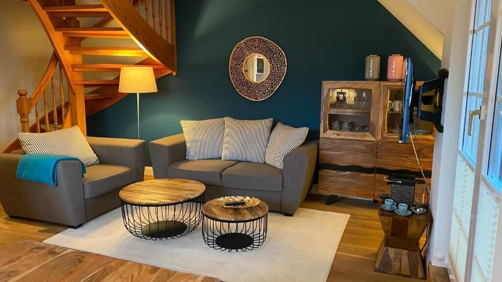 Ein Wohnzimmer mit Treppe, zwei Sofas, einem Couchtisch und einer Vitrine.