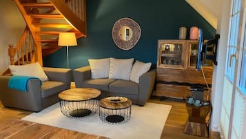 Ein Wohnzimmer mit Treppe, zwei Sofas, einem Couchtisch und einer Vitrine.
