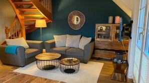 Una sala de estar con una escalera, dos sofás, una mesa de centro y un aparador con puertas de vidrio.