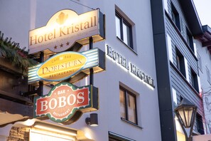 On peut voir les enseignes « Hôtel Kristall », « Café-bar » et « Bobos » sur un immeuble.