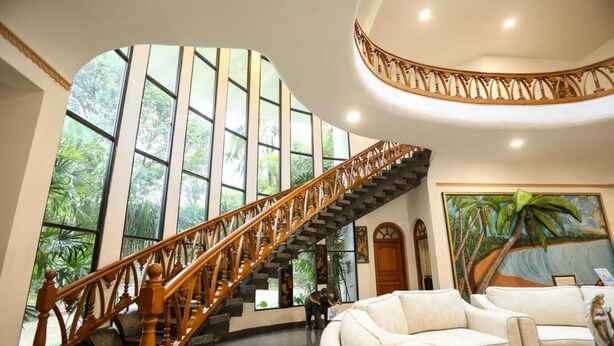 A spacious lobby with a curved staircase, large windows, and a tropical mural. - Airavata Boutique Resort (Kandy)